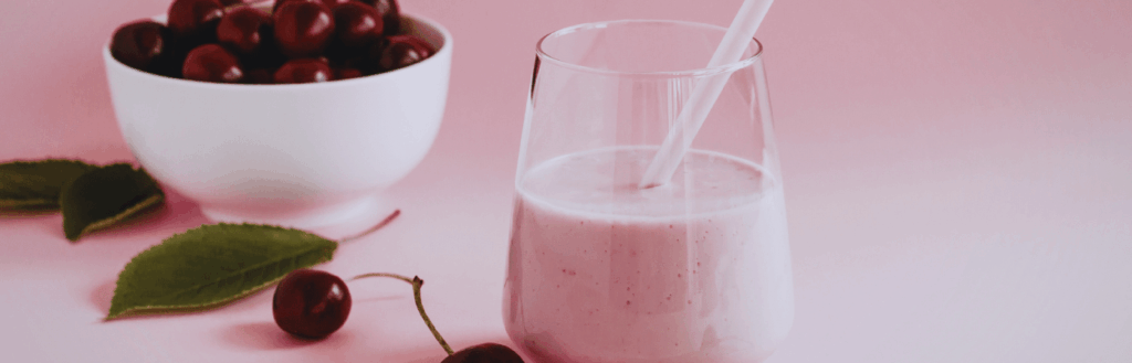 Cherries in a bowl with a sweet cherry smoothie in a glass
