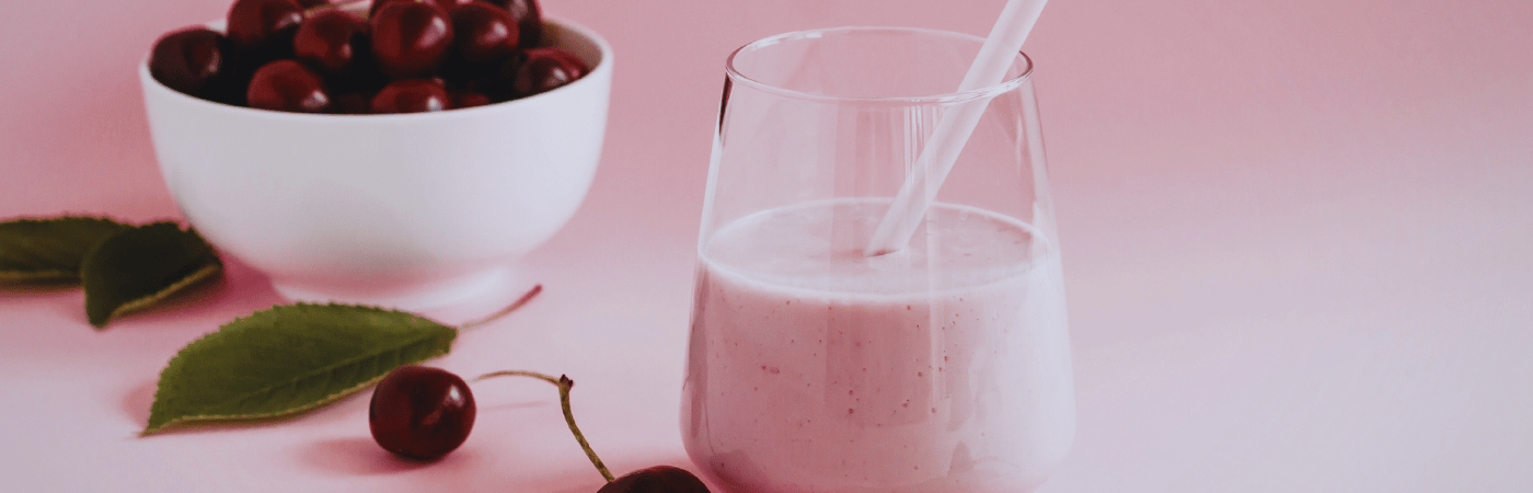 Cherries in a bowl with a sweet cherry smoothie in a glass