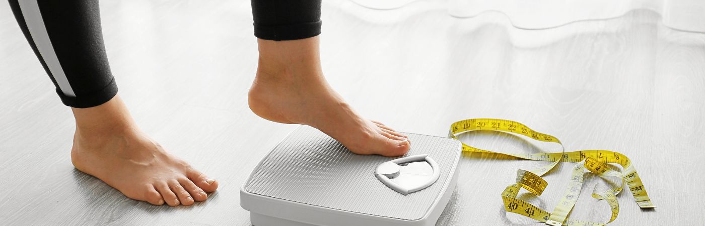 A woman stepping on the scales for weight loss