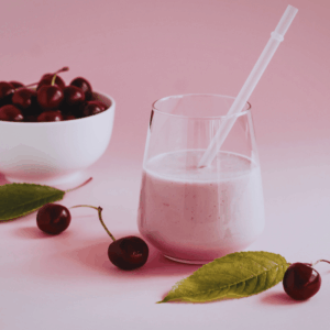 sweet cherry smoothie in a glass with a bowl full of cherries